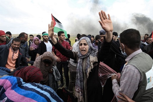 Palestinian protestors wave their national flag and gesture during a demonstration commemorating Land Day near the border with Israel, east of Khan Yunis, in the southern Gaza Strip on March 30, 2018.
Clashes erupted as thousands of Gazans marched near the Israeli border in a major protest dubbed "The Great March of Return". / AFP PHOTO / SAID KHATIB