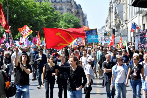 Protesters hold French communist party's flags during a rally called to protest against policies of the French president on the first anniversary of his election, on May 5, 2018 in central Paris. 
Thousands of people demonstrated in central Paris on may 5 amid a heavy police presence to protest against President Emmanuel Macron's sweeping reforms, a year after he came to office. / AFP PHOTO / GERARD JULIEN