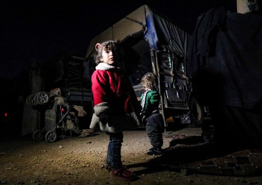 Children stand near the back of a truck near the Omar oil field in the countryside of the eastern Syrian Deir Ezzor province on January 25, 2019, as she arrives with other fleeing families from remaining pockets held by Islamic State (IS) group fighters. - The Syrian Democratic Forces (SDF), backed by air strikes of the US-led coalition, are fighting to expel the last IS fighters from a few hamlets in the eastern province of Deir Ezzor. For days, hundreds have been fleeing what remains of the so-called "Hajin pocket" east of the Euphrates, SDF officials say. (Photo by Delil SOULEIMAN / AFP)