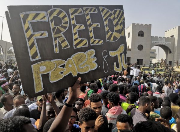 Sudanese anti-regime demonstrators, holding up a banner calling for "Freedom, Peace and Justice" carry on with their protest on April 11, 2019 in the area around the army headquarters in Sudan's capital Khartoum. - The Sudanese army is planning to make "an important announcement", state media said today, after months of protests demanding the resignation of longtime leader President Omar al-Bashir. Thousands of Khartoum residents chanted "the regime has fallen" as they flooded the area around the military headquarters, where protesters have held an unprecedented sit-in now in its sixth day. (Photo by - / AFP)