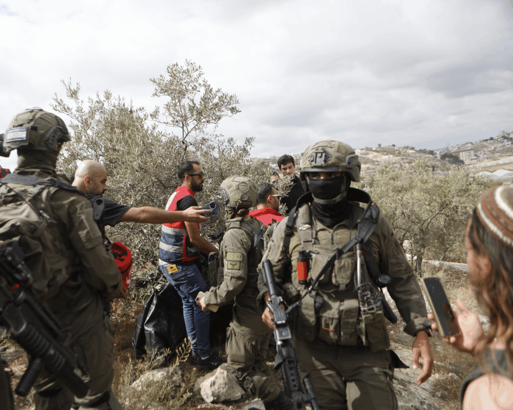 شهرک‌نشینان یهودی در حال اخلال در برداشت زیتون در روستای سوبا در جنوب الخلیل، در حضور نظامیان اسرائیلی. ۲۰ مهر ۱۴۰۴. عکس: مامون وازواز/خبرگزاری آناتولی
