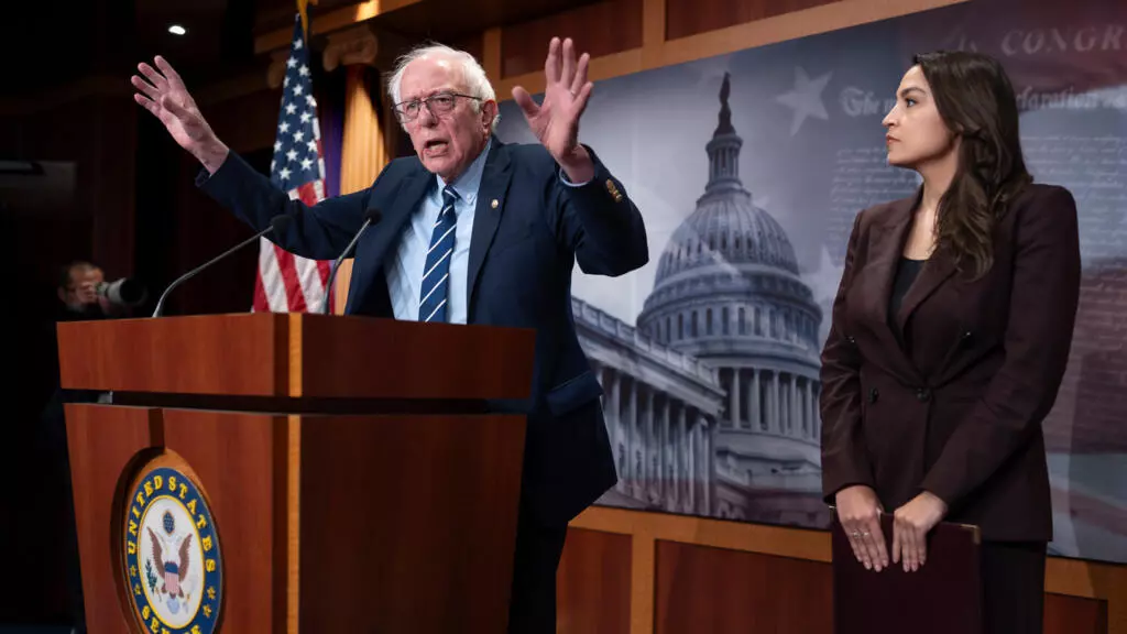 سناتور دموکرات برنی سندرز (سمت چپ) و نمایندهٔ دموکرات الکساندریا اوکازیو-کورتز در کنفرانس مطبوعاتی در ساختمان کنگره در واشنگتن دی سی، ۲۵ مارس ۲۰۲۶. عکس از AP - J. Scott Applewhite