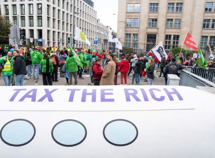 «از ثروتمندان مالیات بگیرید» (Tax The Rich)، شعار سازمان «آکسفام» (Oxfam) در تظاهرات علیه افزایش قیمت انرژی در بروکسل (بلژیک) که سه اتحادیهٔ‌ کارگری برگزار کردند. ۱۲ مه ۲۰۲۶ ـ عکس از خبرگزاری فرانسه.